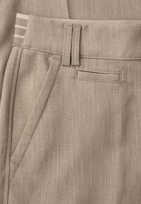 Pantalon beige sur mesure avec poches droites, devant plat et tissu texturé. Comprend une ceinture subtilement rayée.