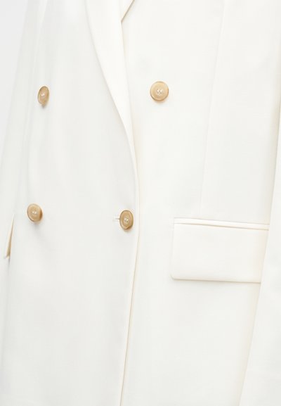 Fehér kétrészes blézer világosbarna gombokkal és jobboldali zsebfedővel.
