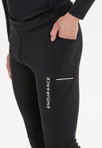 Zwarte sportleggings met een strak ontwerp, een zijzak, reflecterende accenten en een logo met de tekst "ENDURANCE" in het wit.