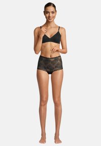 Schwarzes Spitzen-Bralette und hochgeschnittenes Slip-Set. Das Bralette hat verstellbare Träger; der Slip hat einen gewellten Spitzensaum mit floralem Muster. Glatte Textur.