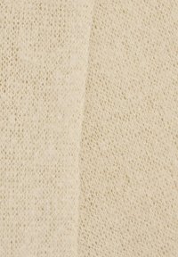 Tela tejida de color crema claro con textura de tejido abierto, que presenta una apariencia suave y ligeramente brillante. Se ven dos secciones.