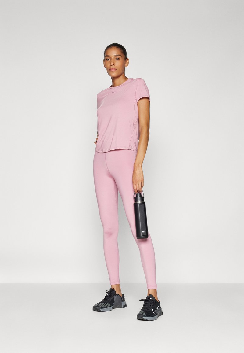 Rosa sporttröja och leggings med en slät yta; kombinerat med svarta träningsskor. Håller en svart vattenflaska.