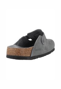 Sandales à enfiler en suède gris avec une semelle en liège, une semelle extérieure en caoutchouc noir et un accent décoratif en forme de bouton sur le côté.
