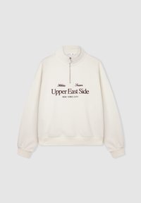 Kremowa bluza z wysokim kołnierzem, zamkiem błyskawicznym i ściągaczami. Posiada napisy "Upper East Side" i "Nowy Jork" w ciemnobrązowym kolorze.