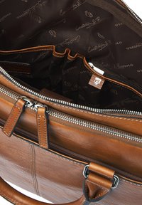 Brown leather briefcase with dual silver zippers open to reveal dark fabric interior lining with logo patterns and multiple small pockets.