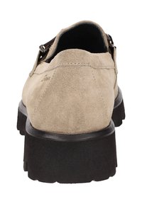 Beige suède instapper met een dikke zwarte zool, zichtbare stiksels en een metalen gespdetail aan de zijkant, vanaf de achterkant getoond.