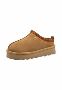 Chaussure slip-on beige avec une tige en suède doux, un bord en textile à motifs et une semelle en caoutchouc durable avec une légère élévation de plateforme.