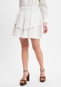 Weißer, schichtweise Rock mit elastischem Bund, verziert mit einem floralen Muster in Hellblau und Gelb. Vervollständigt mit braunen High-Heels-Sandalen.
