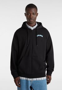 Czarna bluza z kapturem na zamek błyskawiczny, z przednimi kieszeniami, niebieskie logo "VANS" na klatce piersiowej, sznurki w kapturze, warstwowa na koszulę w kratę, casualowy krój.