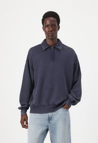 Felpa blu navy con zip, colletto a risvolto, vestibilità comoda e polsini a costine. Realizzata in tessuto morbido, con una texture effetto vintage.