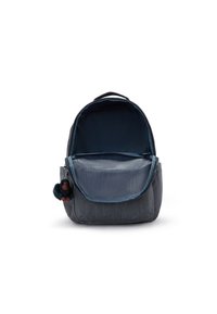 Mörkblå denimryggsäck med huvudfacket helt öppet, som har en dragkedja och en liten ansluten plyschapa som nyckelring.