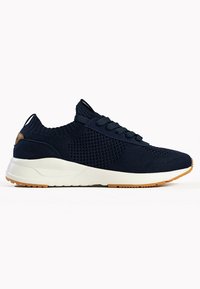 Sneaker sportivo blu navy con tomaia in maglia, pannelli in mesh testurizzati e suola bianca. Presenta lacci tondi e suola in gomma.