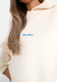 Felpa con cappuccio color crema con ricamo blu "Sixth June". Presenta una vestibilità comoda e una texture morbida, ideale per l'abbigliamento casual.
