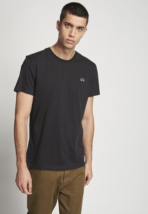 Schwarzes Baumwoll-T-Shirt mit Rundhalsausschnitt und kurzen Ärmeln, das ein kleines gesticktes Design auf der linken Brust zeigt. Glatte Textur.