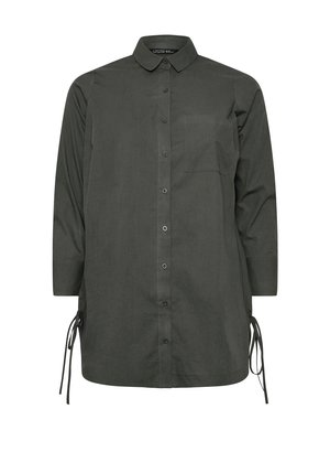 Camisa de color verde oscuro, con botones, de manga larga, un cuello y un bolsillo en el pecho. Cuenta con lazos ajustables en los laterales para un mejor ajuste. Textura de tela suave.