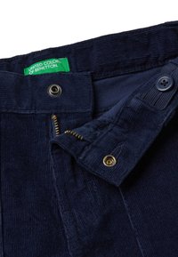 Námořnické kordové kalhoty se zipem, kovovými doplňky a zelenou visačkou s nápisem "United Colors of Benetton." Strukturovaná, ribbovaná tkanina.