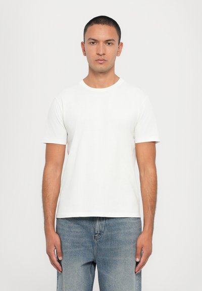 Witte katoenen T-shirt met korte mouwen, ronde halslijn en een relaxte pasvorm, gecombineerd met lichtblauwe denim jeans. Minimalistisch ontwerp, geen patronen.