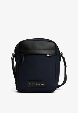 Borsa a tracolla blu navy con parte superiore in pelle sintetica nera, tracolla regolabile e una toppa con logo. Presenta una texture liscia e una chiusura con zip.