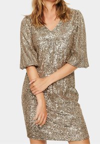 Paljettklänning i guld, med V-ringning, korta puffärmar och en figurnära silhuett. Texturen är slät med reflekterande accenter.