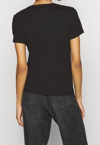 Camiseta de algodón negra de manga corta con cuello redondo, que presenta una textura suave y un diseño simple y clásico.