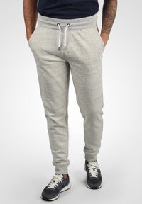 Hellgraue Jogginghose aus einem weichen, strukturierten Stoff. Mit elastischem Bund und weißen Kordeln sowie seitlichen Taschen. Slim-Fit-Design.