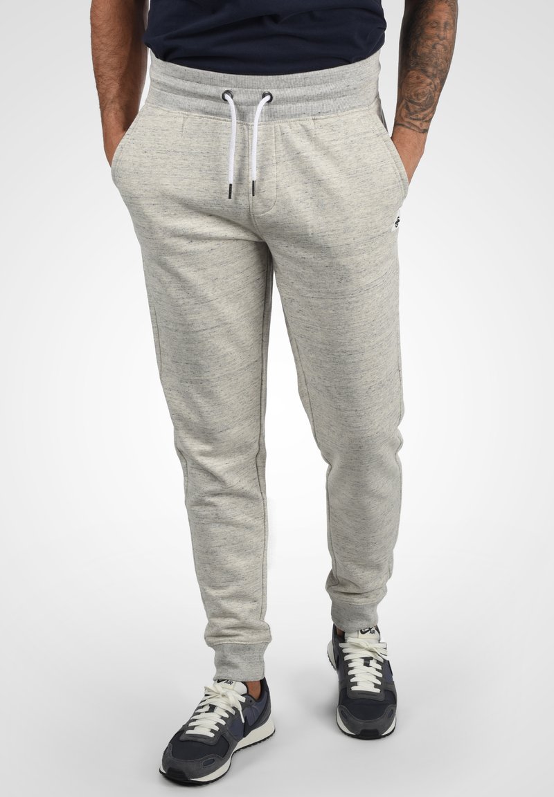 Hellgraue Jogginghose aus einem weichen, strukturierten Stoff. Mit elastischem Bund und weißen Kordeln sowie seitlichen Taschen. Slim-Fit-Design.