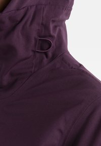 Purpurowa kurtka z kapturem, charakteryzująca się gładką, matową fakturą, regulowanym kołnierzem z troczkiem oraz brakiem widocznych akcentów metalowych.