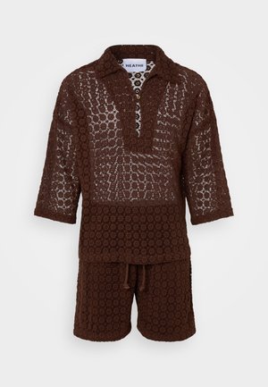 Braunes gehäkeltes zweiteiliges Outfit, bestehend aus einem polierten Oberteil mit halber Knopfleiste und Shorts, das ein offenes, kreisförmiges Muster präsentiert.