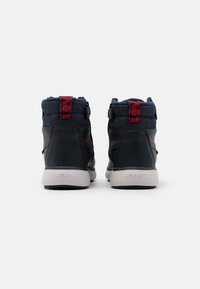 Paire de baskets montantes noires et bleu marine avec semelles blanches, marquage rouge Levi's sur la languette du talon et "Levi's" embossé à l'arrière de la semelle.