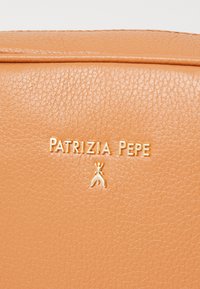 Borsa in pelle testurizzata color tabacco con logo dorato "PATRYZIA PEPE" e un piccolo accento decorativo. Finitura liscia, design minimalista.