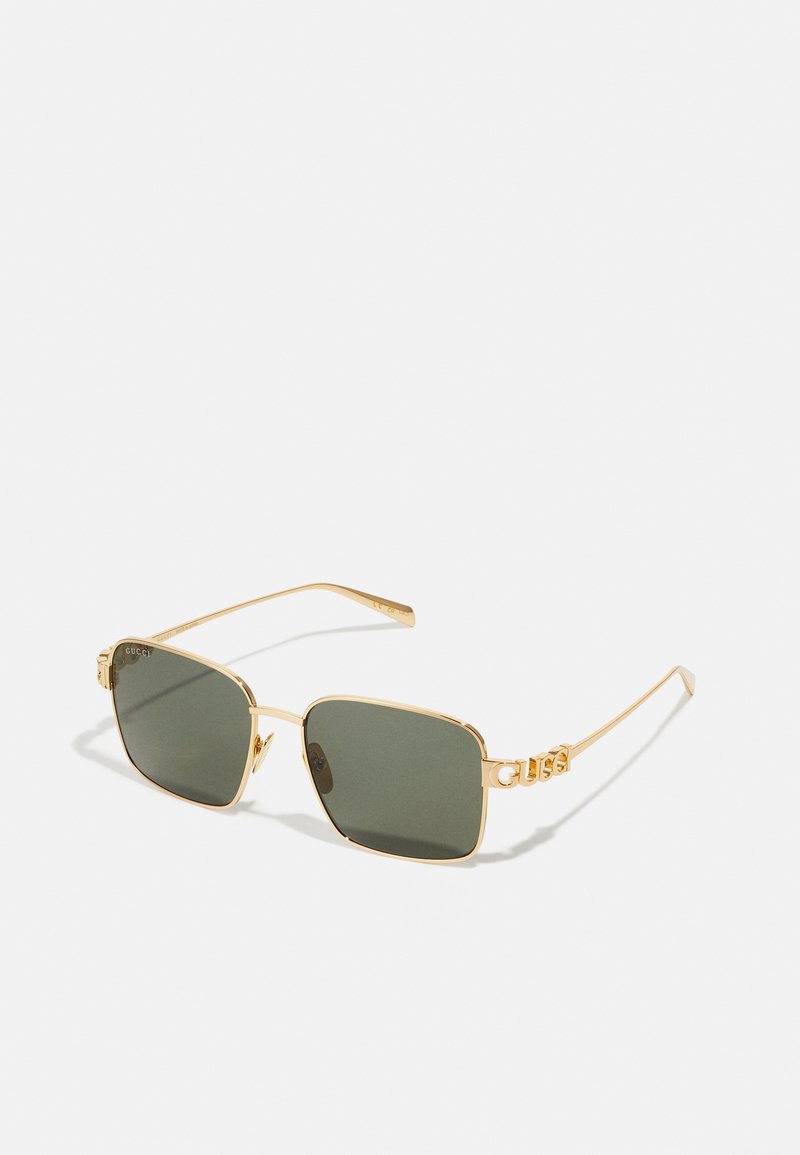 Kultaiset neliönmuotoiset aurinkolasit, joissa on tummanvihreät linssit. Ohut metallirunko, jossa on "Gucci"-logo sankoissa. Tyylikäs muotoilu ja minimalistiset yksityiskohdat.