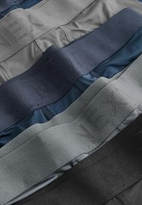 Pila di boxer neri, grigi e blu navy con ampia cintura elastica stampata con la scritta "NEX".