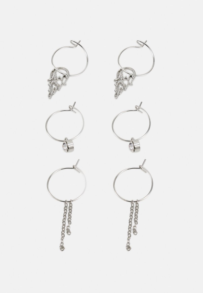 Brincos de argolas em prata com detalhe esculpido, um accentuador de cristal redondo e correntes com elementos pendentes. Várias formas e comprimentos.