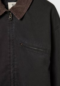 Zwarte jas met een bruin corduroy kraag, uitgerust met een rits borstzak en een gestructureerde stof. Klassiek ontwerp met praktische elementen.