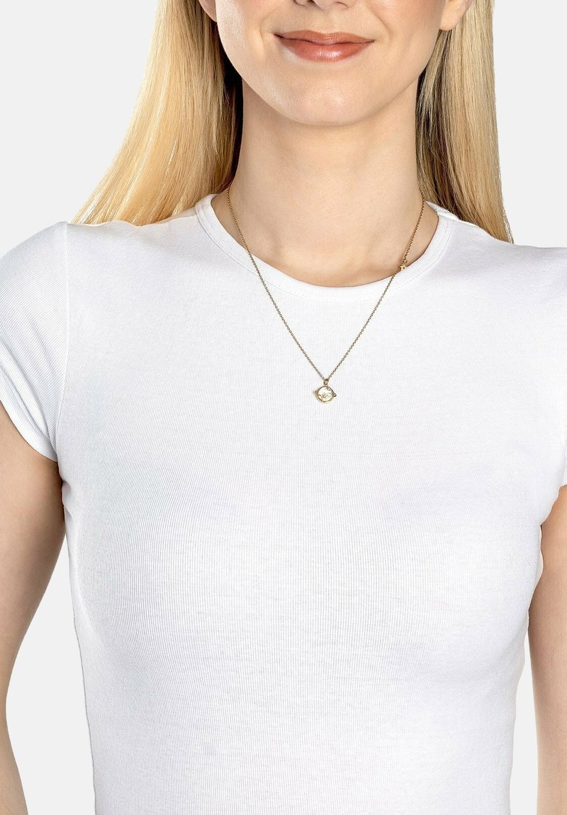 Guldhalskæde med en tekstureret geometrisk vedhæng, båret over en tætsiddende hvid ribbet t-shirt, der fremhæver halskædens glans og design.