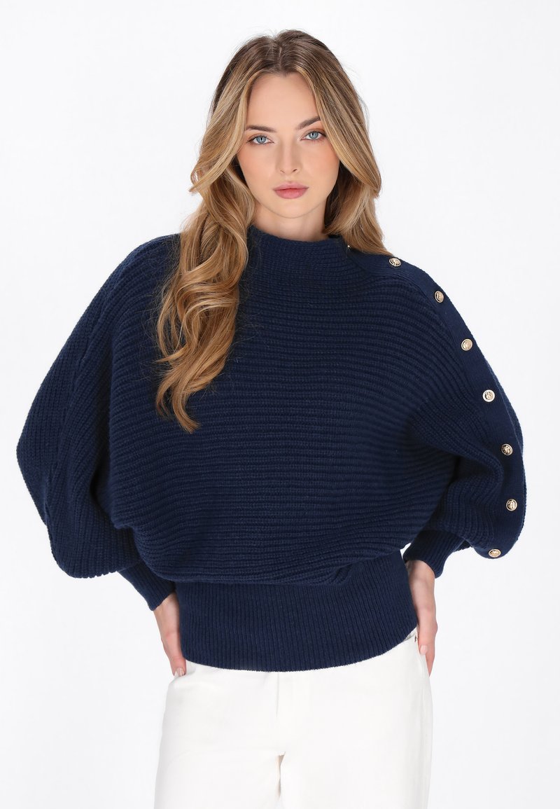 Maglione in maglia blu navy con un design a coste testurizzate, dotato di un collo alto e dettagli con bottoni dorati sulla spalla sinistra e sui polsini.