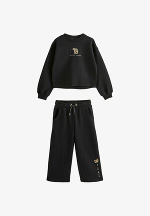 Conjunto de sudadera corta de manga larga negra y pantalones de pierna ancha con el logo dorado "TB by Ted Baker" en el pecho y en la pierna del pantalón, pantalones con cintura elástica.