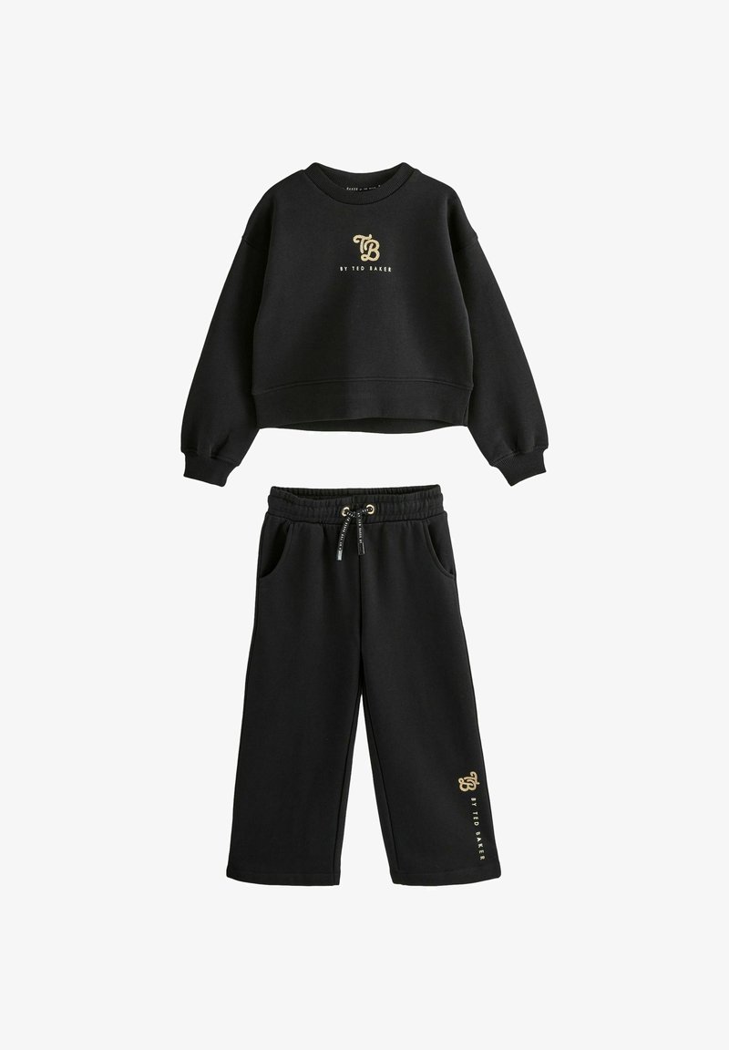 Melna garām piedurknēm īsā sporta krekla un platā kāju bikses komplekts ar zelta "TB by Ted Baker" logo uz krūšu un biksēm, bikses ar elastīgu jostu.