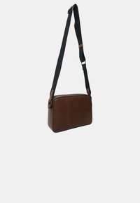 Borsa a tracolla rettangolare marrone con tracolla nera regolabile e chiusura con cerniera su sfondo chiaro.