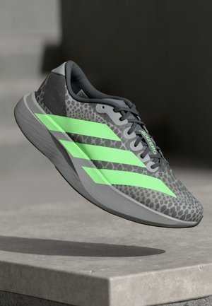 Grey running shoe with a patterned upper, featuring three bright green stripes and a textured heel, designed for lightweight performance.