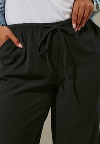 Svarta pyjamabyxor i ett texturerat tyg, med elastisk midja, dragsko och sidofickor.