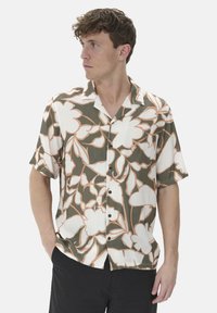 Short-sleeve shirt in lightweight fabric with a green, white, and peach floral pattern; features a camp collar and black buttons.