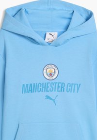 Sweat à capuche bleu clair avec le logo Manchester City, le texte "MANCHESTER CITY" et le logo Puma au centre devant sous la capuche.