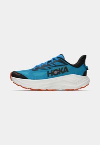 Blå og svart atletisk løpesko med tykk hvit såle og oransje yttersåle, med HOKA-logo på siden og blå skolisser.