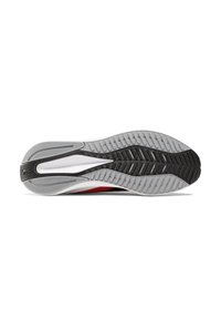 Semelle de chaussure de sport avec une section en caoutchouc noir texturé, une semelle intermédiaire grise avec des rainures, et un accent rouge sur le côté.