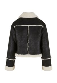 Veste noire cropped avec doublure en fausse fourrure et coutures blanches. Présente un col en V et des poignets roulés. Texture douce avec un design structuré.