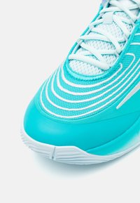 Turkise sportssko med mesh-overdel, tekstureret design og gummisål. Har hvide detaljer og en strømlinet form for optimal ydeevne.