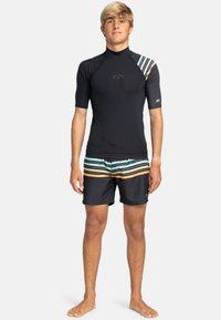 Kortärmad svart våtdräkt med flerfärgade randiga detaljer på axlarna, i kombination med svarta simshorts med ränder.