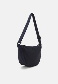 Borsa a tracolla blu scuro in tessuto morbido, con forma arrotondata, tracolla regolabile e chiusura con zip. Design minimalista con texture sottile.