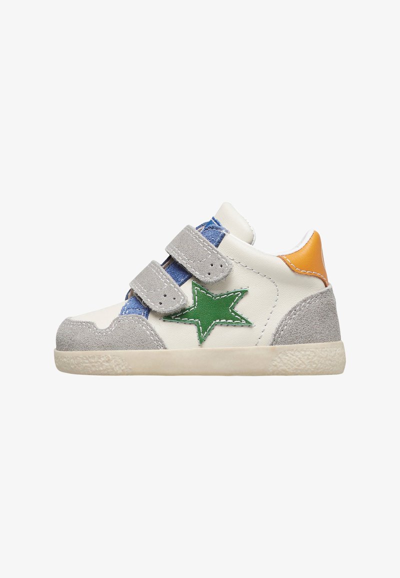 Zapatillas blancas para niño pequeño con detalles en ante gris, parche en forma de estrella verde, tirador naranja en el talón, lengua azul y doble correa de velcro gris.